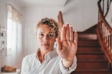 Çekici beyaz kadın portresi uzanmış elleriyle evinin oturma odasında dur hareketi gösteriyor. Kendine güveni tam bir kadın. Reddetme ya da reddetme işareti var. 