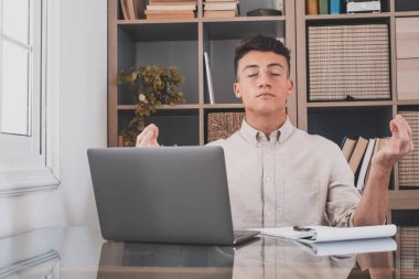 Serene ofis erkeği, masa başında oturup yoga yapıyor, stres atağı yorgunluğunu azaltmak için meditasyon yapıyor iş yerinde iç dengeyi hissediyor, farkındalığı geliştiriyor, zihinsel sağlık kavramını koruyor. 