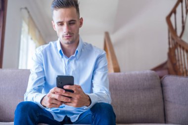 Heyecan gülen adam telefon ekranına bakarak, mobil uygulama kullanarak, sosyal ağda mesaj yazarak, haber okuma, e-posta, arkadaşlarınızla sohbet erkek öğrenci, oyun oynarken, komik video izlerken  
