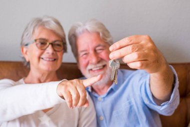 Close up of senior couple showing keys of house. Elderly couple holding keys for investment of property concept. Satisfied old couple holding keys to their new house   clipart