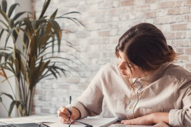 Gülümseyen kadın notlar yazıyor. Dizüstü bilgisayarda webinar çalışmalarını izliyorlar. Genç öğrenci bilgisayar dersi öğreniyor. 