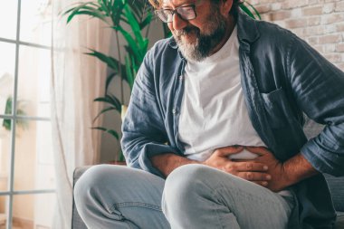 Şiddetli mide ağrısı çeken bir adam evde oturuyor. Karnı ağrıyan, ishal ya da hazımsızlık çeken bir adamın eli. Kafkasyalı adam, acı verici bir şekilde karnına bastırıyor.  