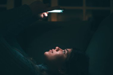 Güzel bir genç kadın, gece geç saatlerde evde, kanepede telefonu tutuyor ve kullanıyor. İnternette sörf yapan arkadaşlarıyla sohbet eden genç bir kız. Teknoloji ve internetin tadını çıkarıyor.