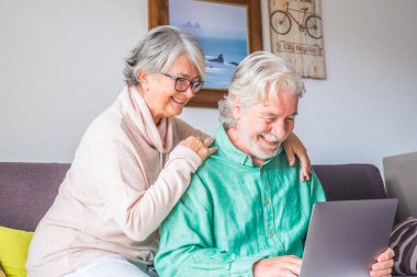 İki yaşlı ve olgun insan evlerinde kanepede birlikte tablet kullanıyorlar. Sunbae, dizüstü bilgisayarı kullan ve izlemekten zevk al. Boş ve boş zaman kavramı 