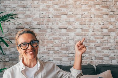 Mutlu ve neşeli bir kıvırcık kadının portresi ve kapanışı. Kameraya bakıyor ve duvarda fotokopi alanı ya da yazacak yer olan bir şey gösteriyor.. 