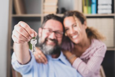 Mutlu çift yeni evlerinin ya da ofislerinin anahtarlarını gösteriyor. Kocasının elinde yeni dairelerinin anahtarı olan gülümseyen bir eş portresi. İki kiracı ya da kiracı taşınıyor ya da elinde anahtarlarla taşınıyor 