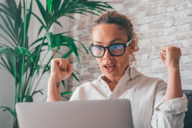 Kanepede oturan kadın dizüstü bilgisayarda harika haberler okurken kucağına sıkılmış yumruklar çığlıklar atıyor. Kumarbaz online açık artırma zaferini kutluyor. İnanılmaz bir mutluluk teklifi aldım. 