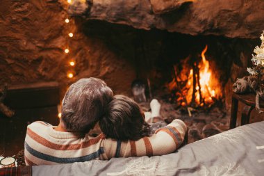 Yaşlı beyaz çift boş zamanlarını evde geçiriyorlar. Romantik karı koca, kış tatilinde yanan şömineye bakarken dinleniyorlar. 