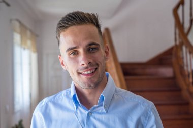 Mutlu bir milenyum erkeğinin portresi evde dinlenen kameraya bakıyor. Uzayı kopyala Dairedeki koltukta oturan kendine güvenen adam fotoğraf çekiyor. Kapat. 