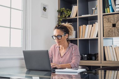 İnternette çalışırken gülümseyen Kafkasyalı genç iş kadını laptopta webinar podcast izliyor ve eğitim konferansına çağırıyor notlar alıyor çalışma masasına oturuyor, e-öğrenim konsepti oluşturuyor. 