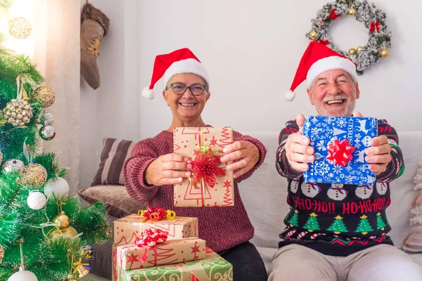 Old people having fun and showing at the camera their gift or present at the camera -  celebrating Christmas together