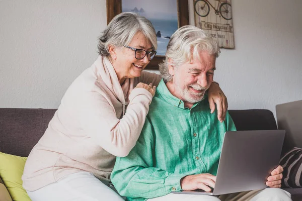 stock image Couple of two old and mature people at home using tablet together in sofa. Senior use laptop having fun and enjoying looking at it. Leisure and free time concept  