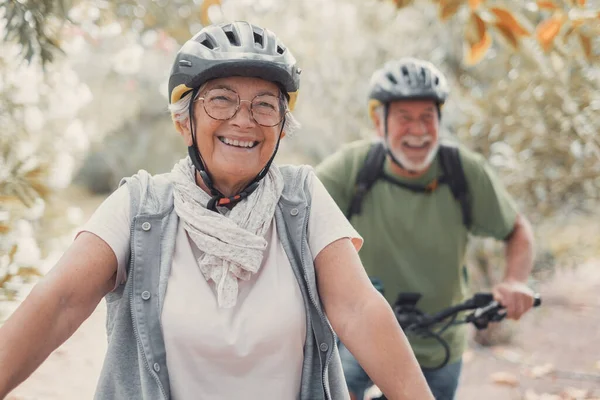 stock image Portrait of one old woman smiling and enjoying nature outdoors riding bike with her husband laughing. Headshot of mature female with glasses feeling healthy. Looking at the camera