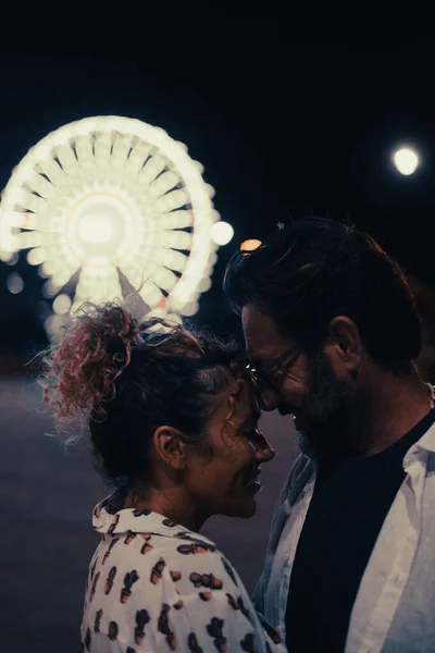 夜になるとライトアップされた観覧車の前で熱烈に抱き合う夫婦 カップルロマンスと夜の休暇中に屋外で質の高い時間を過ごす — ストック写真
