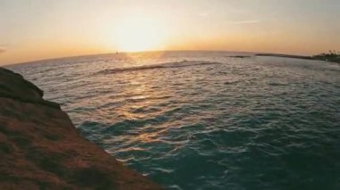 Pov ve genç bir adamın arka planda günbatımı olan bir uçurumdan atladığını gören ilk kişi. Tatiller ve seyahatler. Tenerife 'de tek başına denize atlayan bir yaz tatili.