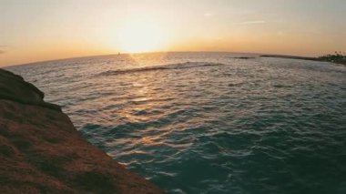 Pov ve genç bir adamın arka planda günbatımı olan bir uçurumdan atladığını gören ilk kişi. Tatiller ve seyahatler. Tenerife 'de tek başına denize atlayan bir yaz tatili.