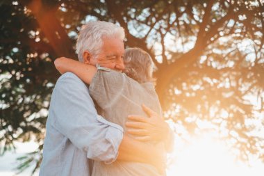 Head shot close up portrait happy grey haired middle aged woman snuggling to smiling older husband, enjoying tender moment at park. Bonding loving old family couple embracing, feeling happiness.
