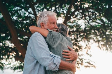 Head shot close up portrait happy grey haired middle aged woman snuggling to smiling older husband, enjoying tender moment at park. Bonding loving old family couple embracing, feeling happiness.