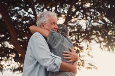 Head shot close up portrait happy grey haired middle aged woman snuggling to smiling older husband, enjoying tender moment at park. Bonding loving old family couple embracing, feeling happiness.