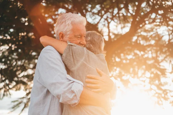 Head shot close up portrait happy grey haired middle aged woman snuggling to smiling older husband, enjoying tender moment at park. Bonding loving old family couple embracing, feeling happiness.