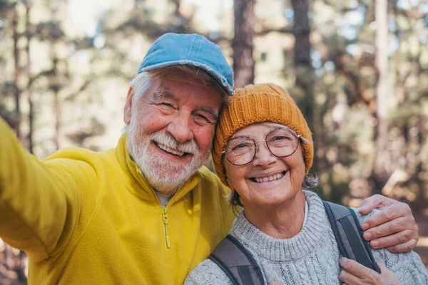 stock image Head shot portrait close up of cute couple of old seniors taking a selfie together in the mountain forest looking at the camera smiling having fun enjoying. Two mature people hiking.