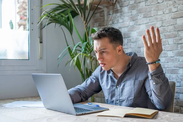 Stock image Unhappy young caucasian male worker in glasses look at laptop screen shocked by gadget breakdown or operational problems. Frustrated man confused surprised by unexpected error on computer device.