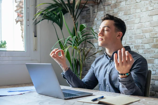 stock image Serene office male employee sit at desk relaxing doing yoga, practice meditation to reduce stress relief fatigue feel internal balance at workplace, improve mindfulness, maintain mental health concept