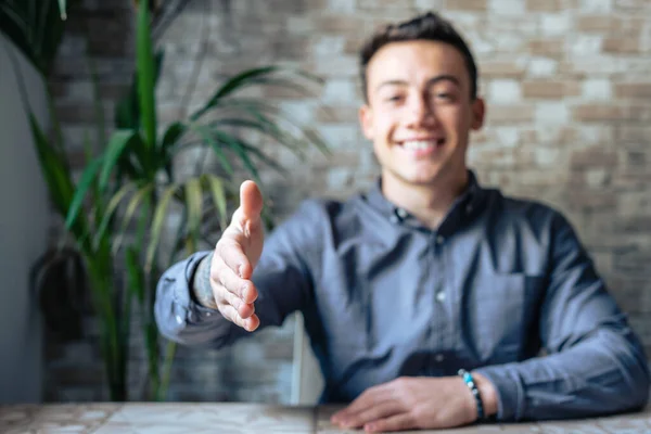 Portrait of happy young male hr stretching hand inviting you spectator to join corporate team, friendly capable manager looking at camera extending hand for handshake welcoming new client or colleague