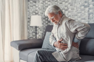 Upset senior elder man feel sudden back pain muscles ache tension injury sitting at home, sad old grandfather touching spine having lower lumbago backache osteoarthritis arthritis, backache concept