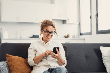 Heyecanlı, mutlu, genç bir kadın cep telefonundan mesaj okuyor, ekrandan iyi haberler alıyor, gülümsüyor, gülüyor, video görüşmeleri yapıyor, internette sohbet ediyor, online uygulama kullanıyor. İletişim konsepti