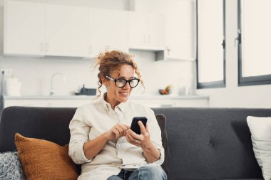 Heyecanlı, mutlu, genç bir kadın cep telefonundan mesaj okuyor, ekrandan iyi haberler alıyor, gülümsüyor, gülüyor, video görüşmeleri yapıyor, internette sohbet ediyor, online uygulama kullanıyor. İletişim konsepti