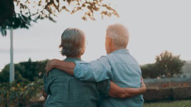 Gün batımında parkta kucaklaşan romantik yaşlı çiftin görüntüleri.