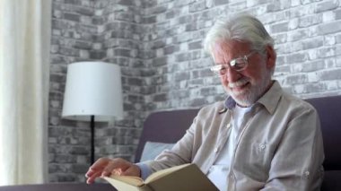 Yaşlı adamın evdeki kanepede kitap okuduğu görüntüler.