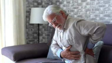 Upset senior elder man feel sudden back pain muscles ache tension injury sitting at home, sad old grandfather touching spine having lower lumbago backache osteoarthritis arthritis, backache concept