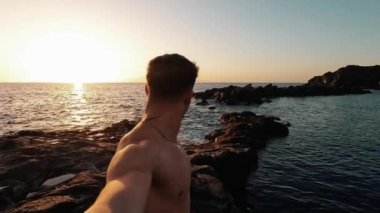 Yakışıklı delikanlının deniz kıyısında günbatımının keyfini çıkardığı görüntüler.
