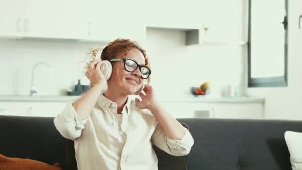 Кадри Красивої Дорослої Жінки Слухає Музику Навушниками Вдома — стокове відео