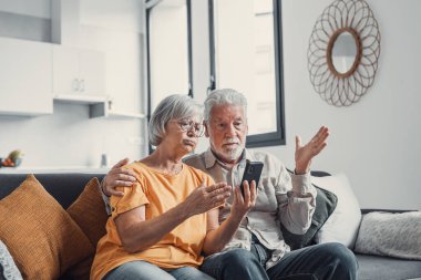 Kötü haber alan yaşlı çift şok oldu, dolandırıcılık, para çalmak, kayıp, aşırı harcama, mali sorun, hesap makinesi tutmak, telefon kullanmak, monitöre bakmak.