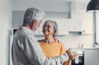 Neşeli aktif yaşlı emekli romantik çift oturma odasında gülerek dans, mutlu orta yaşlı karısı ve yaşlı koca evde eğlenmek, gülümseyen yaşlı aile dedesi birlikte bağ rahatlatıcı