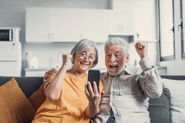 Happy Older Couple Sit Couch Staring Cellphone Screen Gesturing Looking — Foto de Stock