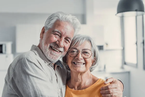 stock image Headshot portrait of smiling elderly 60s husband and wife standing relax hugging cuddling, happy mature old couple rest in living room embrace look at camera show love and care