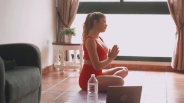 Evdeki oturma odasında yoga yapan güzel bir genç kadının görüntüleri.