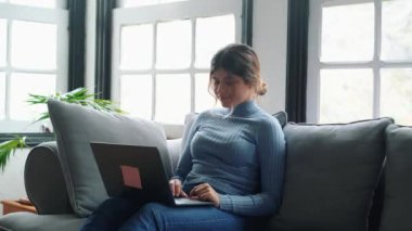 Evde dizüstü bilgisayarla çalışan güzel bir genç kadının görüntüleri.