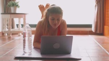 Evdeki oturma odasında yoga yapan güzel bir genç kadının görüntüleri.