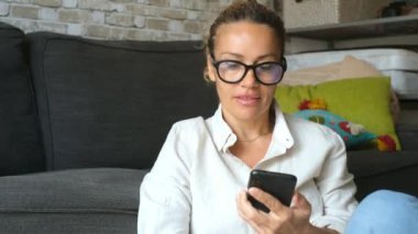Evde akıllı telefon kullanan güzel yetişkin bir kadının görüntüleri.
