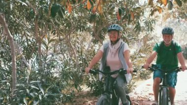 Parkta bisiklete binen güzel yaşlı çiftin görüntüleri.