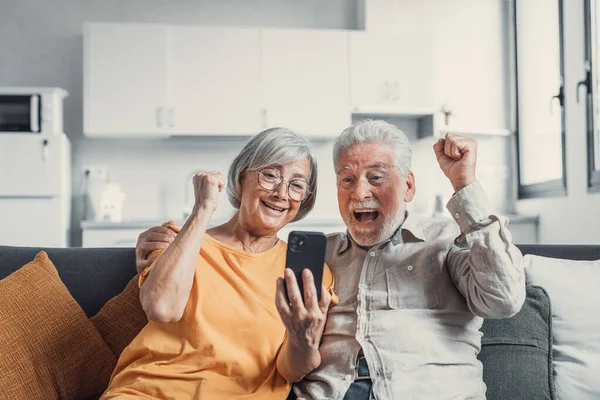 Happy Older Couple Sit Couch Staring Cellphone Screen Gesturing Looking — Foto de Stock