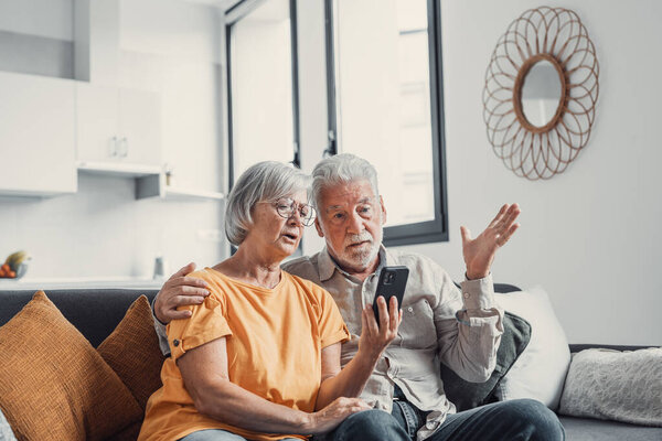 Shocked upset elderly couple getting bad news, finding fraud, money stealing, loss, overspending, financial problem, holding calculator, using phone, staring at monitor