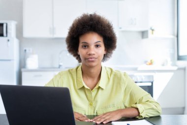 Geçici ciddi kısa saçlı iş kadını iş yerinde dizüstü bilgisayarla oturmuş kameraya bakıyor. Milenyum çalışanı, çalışanı, girişimci portresi