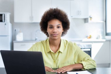 Geçici ciddi kısa saçlı iş kadını iş yerinde dizüstü bilgisayarla oturmuş kameraya bakıyor. Milenyum çalışanı, çalışanı, girişimci portresi