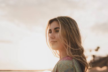 Sahilde denize bakan genç bir kadının portresi. Boş zamanın ve dışarıda özgürlüğün tadını çıkarıyor. Rahatlamak ve mutlu anlar yaşamak..